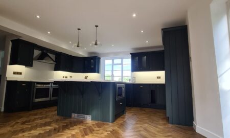 Sprayed olive green kitchen cabinets with brass handles, completed by Lord Hart Decorating Services, featuring a smooth, flawless finish and modern worktop in a contemporary home setting.