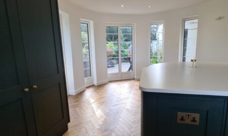 Sprayed olive green kitchen cabinets with brass handles, completed by Lord Hart Decorating Services, featuring a smooth, flawless finish and modern worktop in a contemporary home setting.