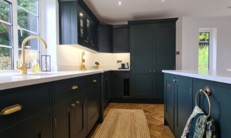 Sprayed olive green kitchen cabinets with brass handles, completed by Lord Hart Decorating Services, featuring a smooth, flawless finish and modern worktop in a contemporary home setting.