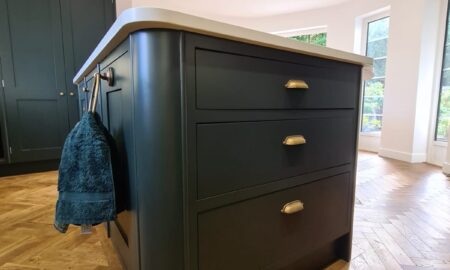 Sprayed olive green kitchen cabinets with brass handles, completed by Lord Hart Decorating Services, featuring a smooth, flawless finish and modern worktop in a contemporary home setting.