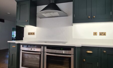Sprayed olive green kitchen cabinets with brass handles, completed by Lord Hart Decorating Services, featuring a smooth, flawless finish and modern worktop in a contemporary home setting