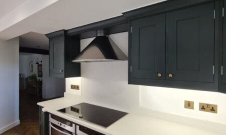 Sprayed olive green kitchen cabinets with brass handles, completed by Lord Hart Decorating Services, featuring a smooth, flawless finish and modern worktop in a contemporary home setting.