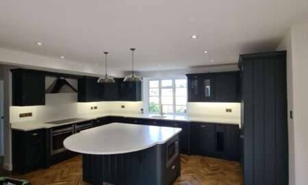 Sprayed olive green kitchen cabinets with brass handles, completed by Lord Hart Decorating Services, featuring a smooth, flawless finish and modern worktop in a contemporary home setting.