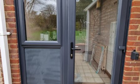 Freshly painted black composite back door and window frame on a brick exterior by Lord Heart Decorating Services