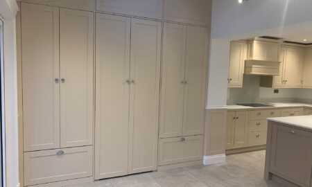 Re-sprayed modern kitchen with refreshed beige cabinetry, a central island featuring a double sink and chrome fixtures, illuminated by pendant lights.