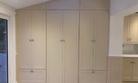 Re-sprayed modern kitchen with refreshed beige cabinetry, a central island featuring a double sink and chrome fixtures, illuminated by pendant lights.
